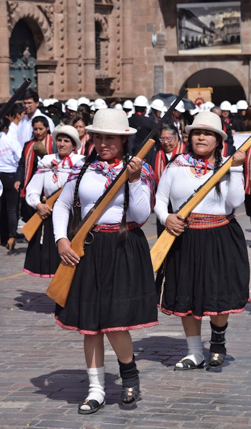 Group of Women in Traditional Clothes Walking with Replica Rifles at a Festival