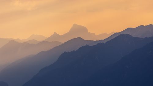 Free Mystical mountain layers beneath an orange sunset, creating a serene and magical landscape. Stock Photo