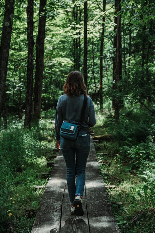 Brunette Woman in Jeans Walking Through Forest