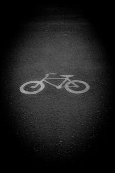 Dark and moody image of a bicycle symbol on an asphalt road, perfect for urban themes.