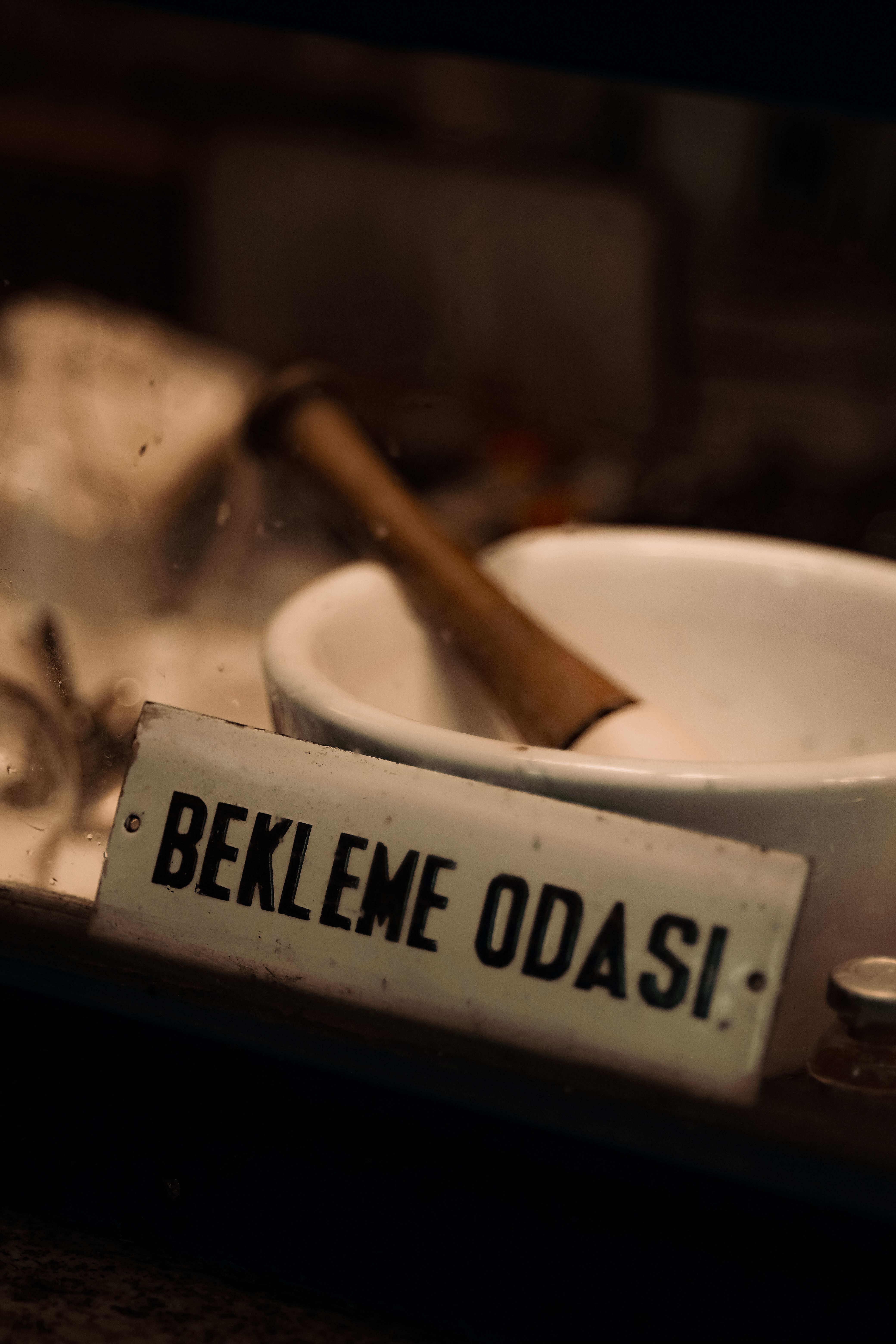 Close-up of a Turkish 'Waiting Room' sign beside a rustic bowl.