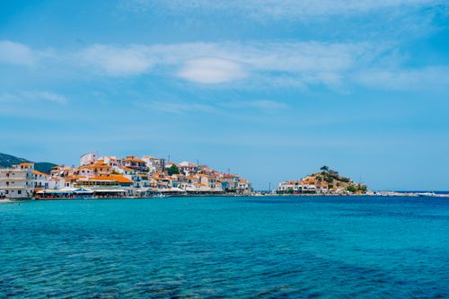 Free Picturesque coastal village with turquoise waters and charming houses on a sunny Mediterranean island. Stock Photo