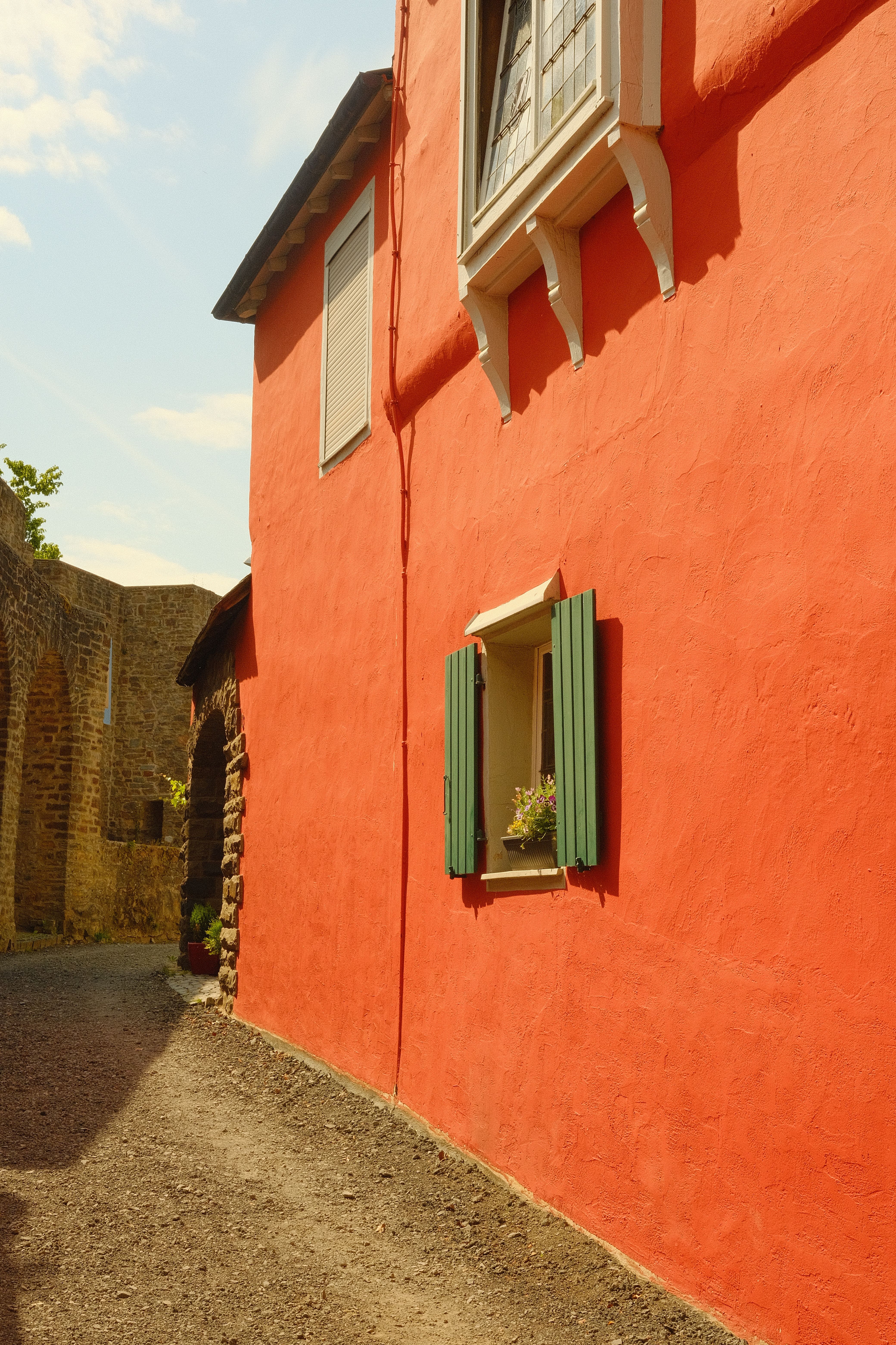 A picturesque red house with green shutters showcasing vintage architecture in a nostalgic town setting.