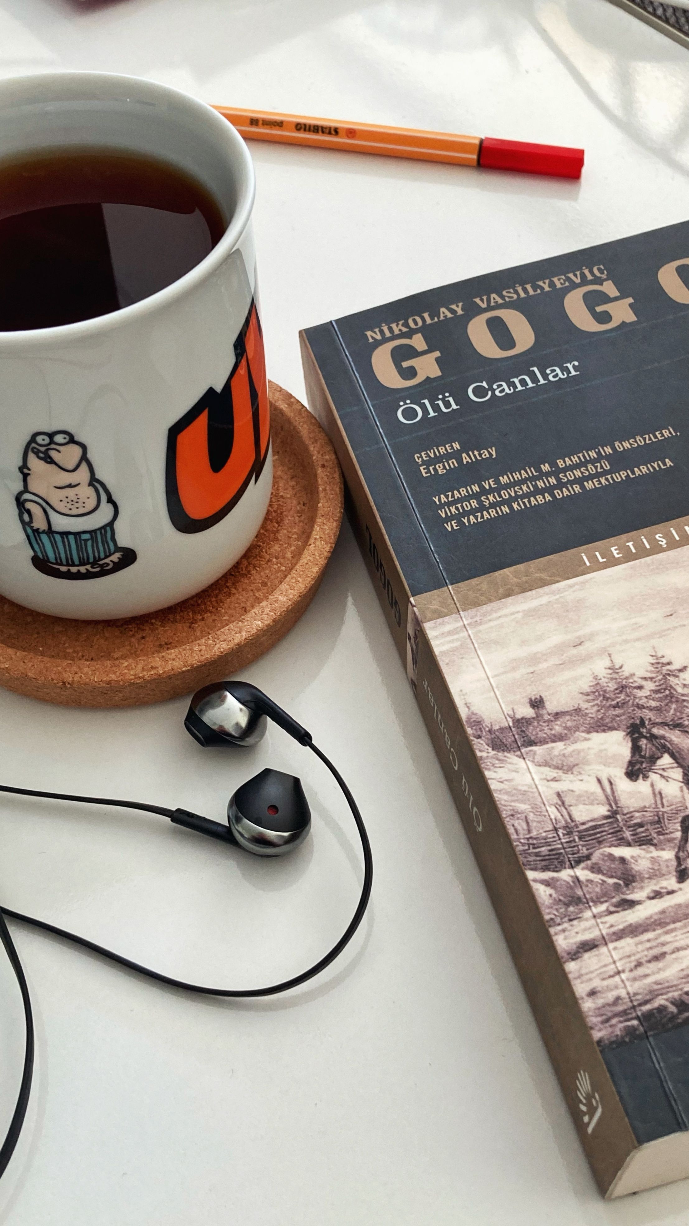 Still life composition featuring a book, mug of tea, and earphones on a table in Ankara.
