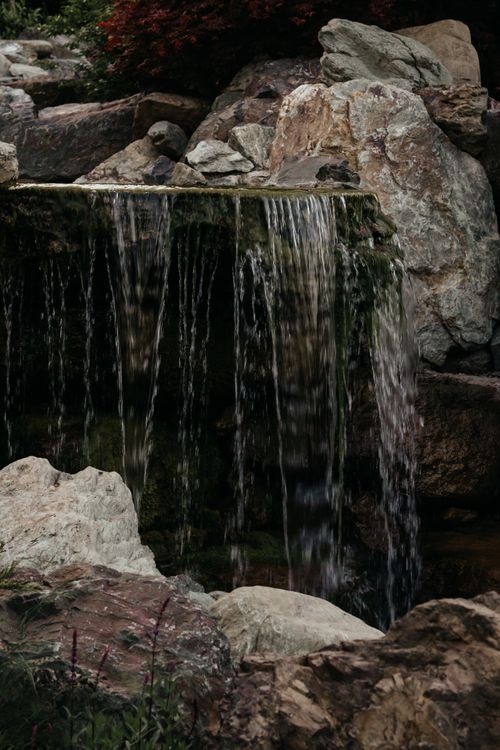 Free A tranquil waterfall cascading over rocks in a lush setting, perfect for relaxation. Stock Photo