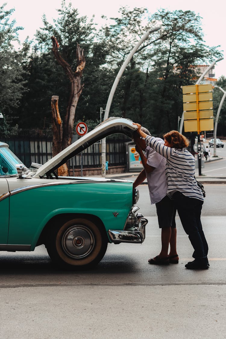 Couple By Broken Vintage Car On Road