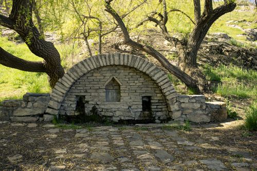 Free An old stone arch nestled among trees in a sunlit grassy park. Stock Photo