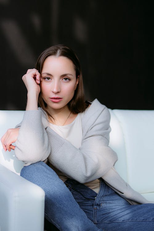 A Woman in a Cardigan Posing on a White Sofa