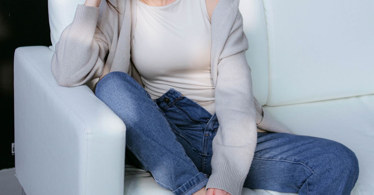 Woman wearing a bronze cami and brown cardigan with jeans