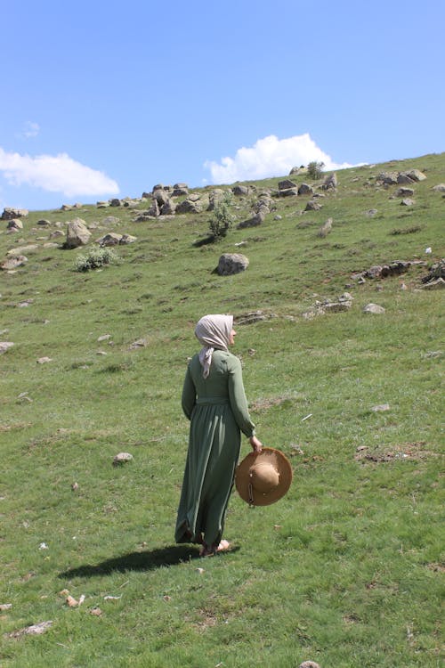 Woman in Hijab and with Hat Standing on Grassland