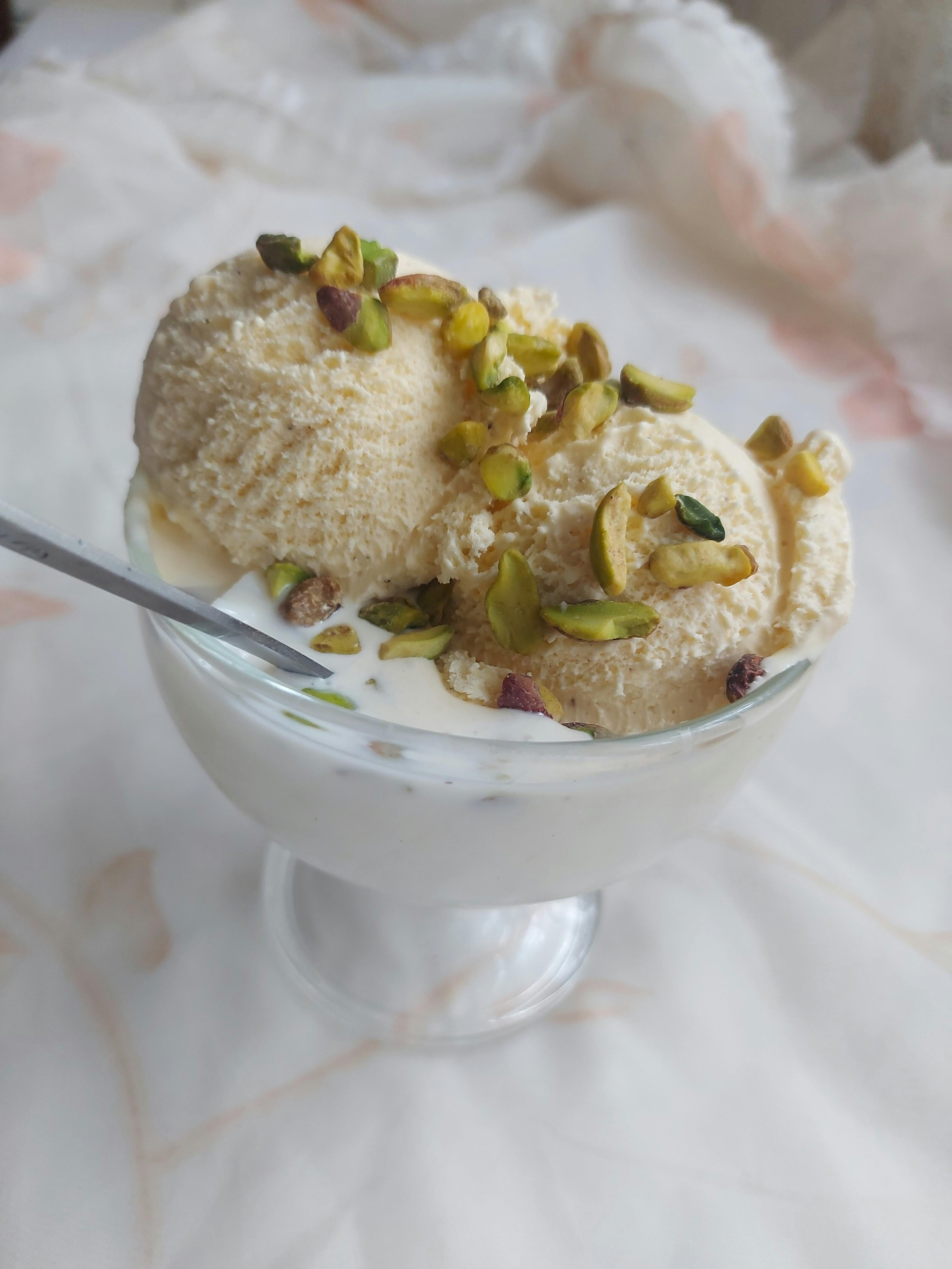 Scoop of creamy pistachio ice cream in a glass cup, garnished with nuts.