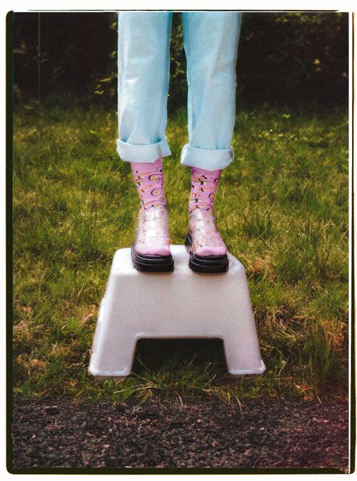 Free Bright pink boots standing on a white stool in a grassy field. Stock Photo