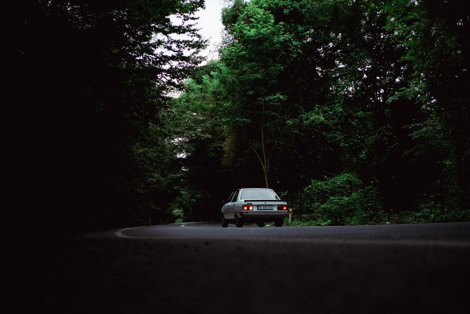 Classic vintage car driving through lush summer forest road in Istanbul, Türkiye.