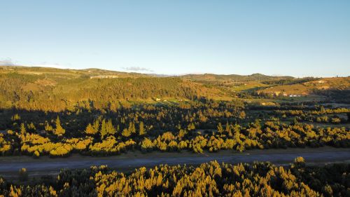 Free Stunning aerial view of Tunja's lush green countryside with trees and hills at sunset. Stock Photo
