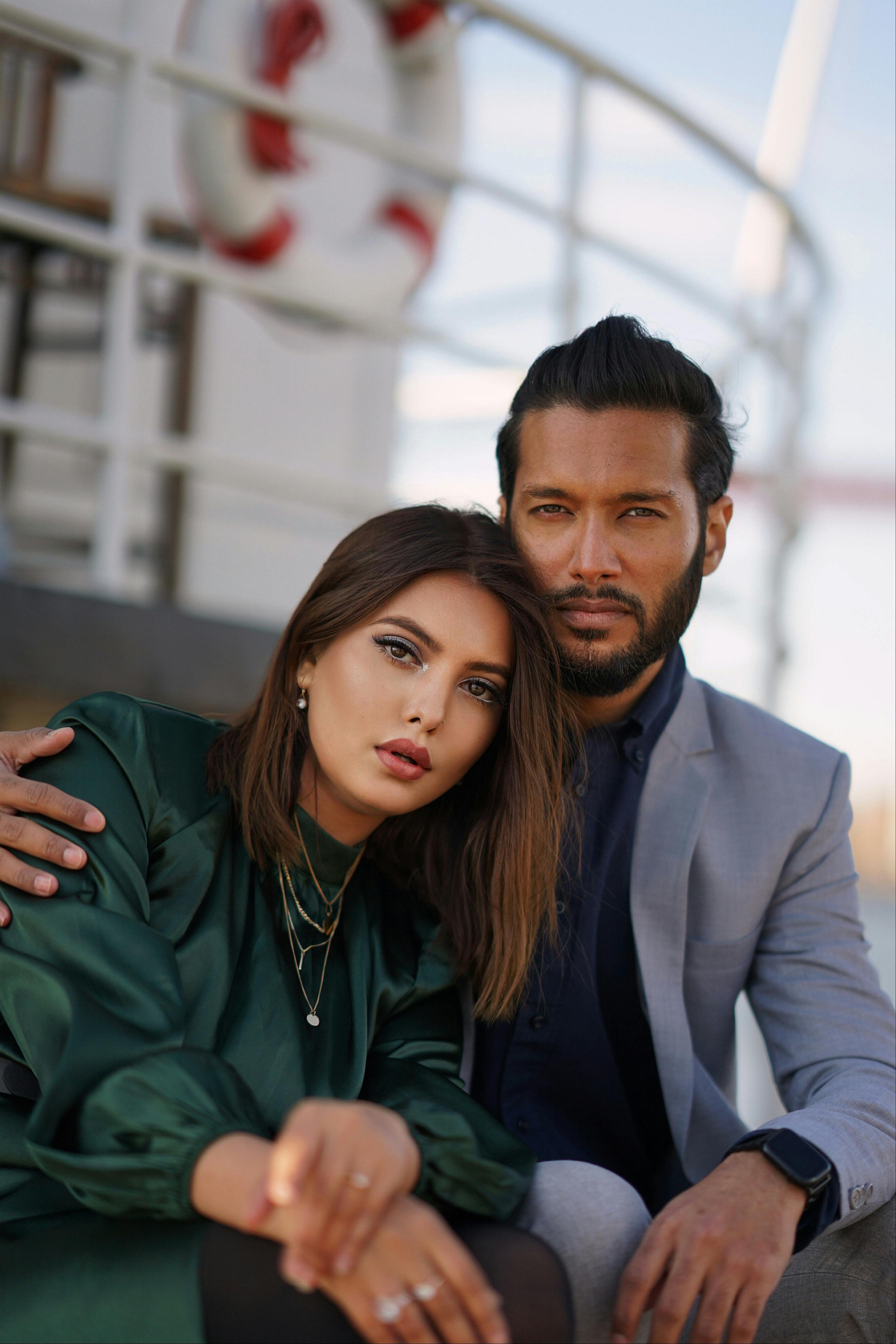 Stylish couple enjoying a relaxed moment on a yacht deck.