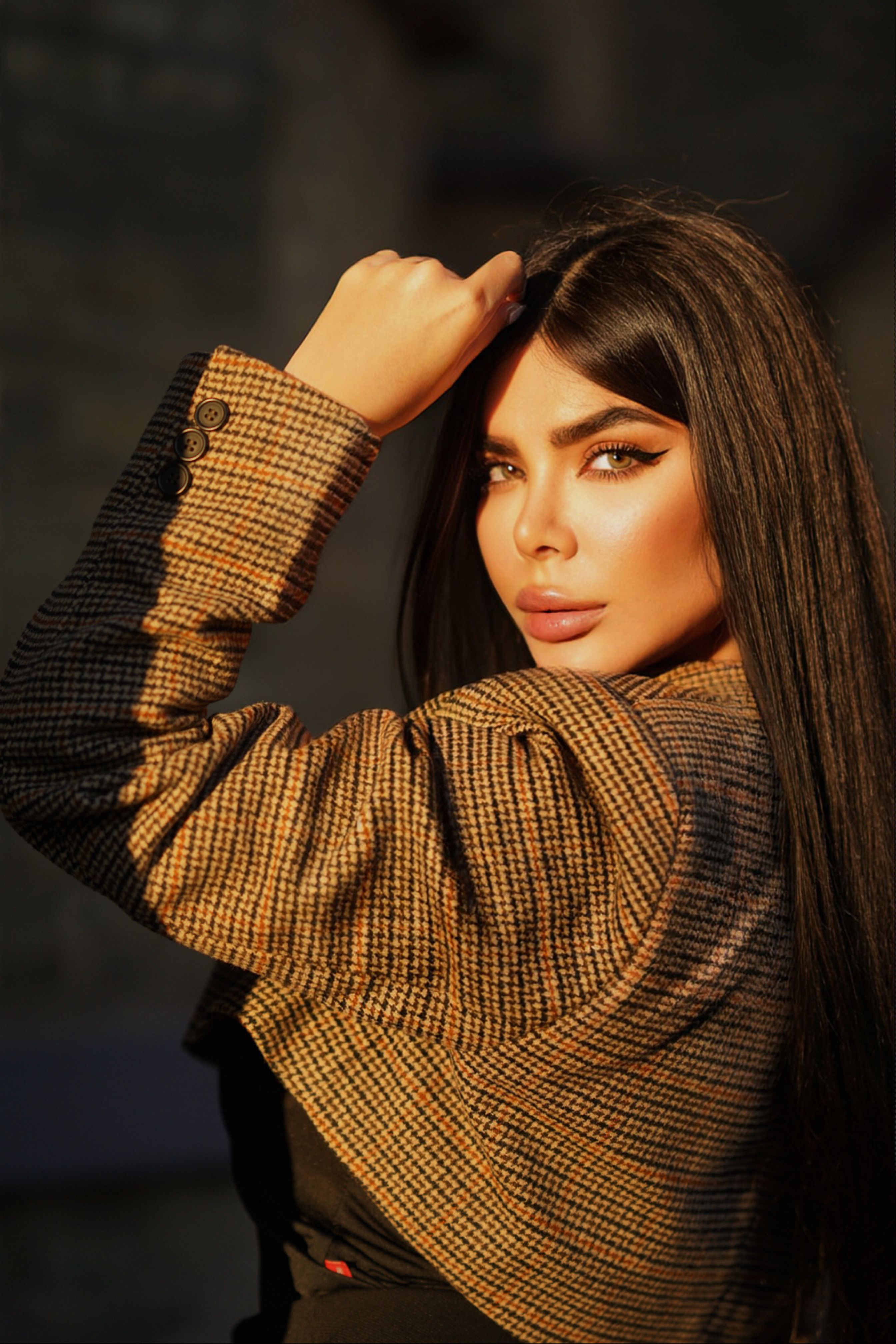 Portrait of a woman in sunlight, showcasing elegance and fashion with a stylish jacket.