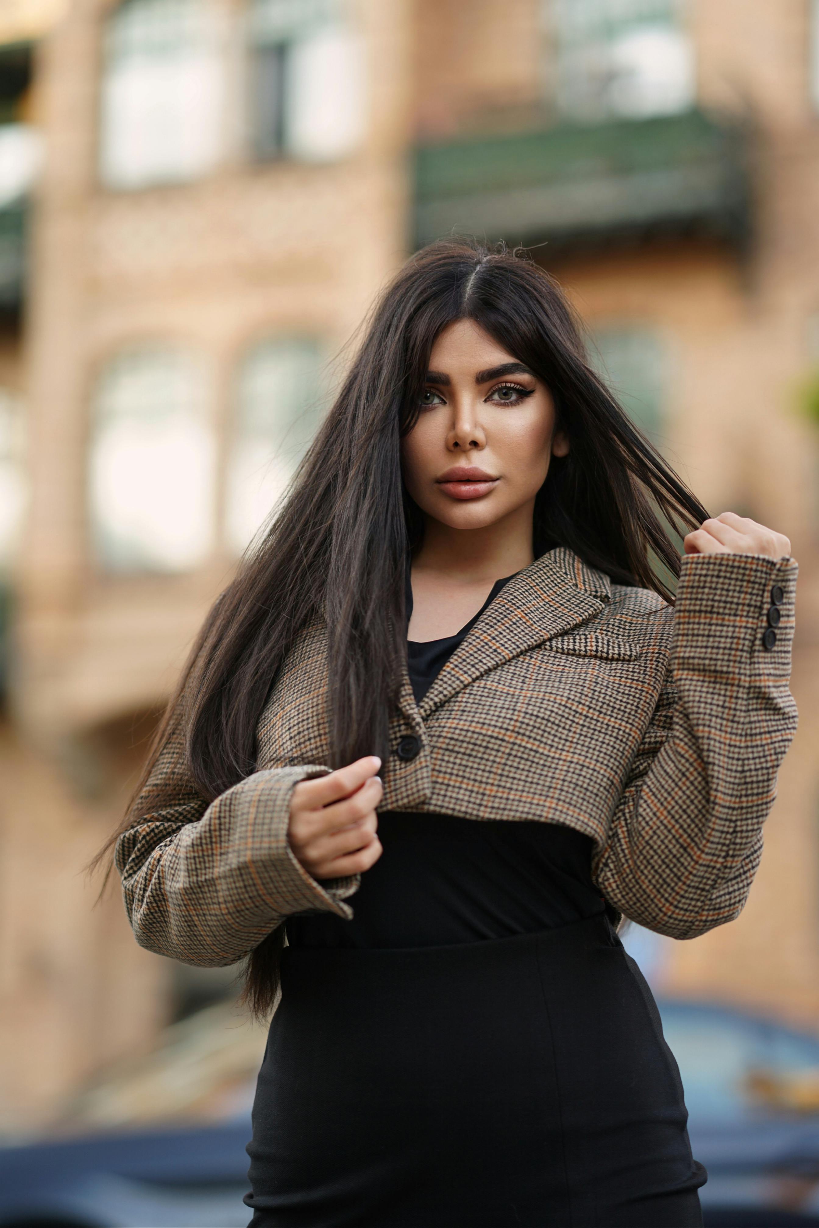 Stylish woman in beige jacket posing on city street for fashion photography.