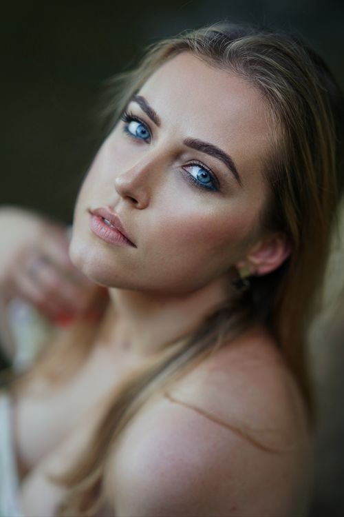 Free Artistic portrait of a woman with striking blue eyes, showcasing beauty and elegance in a soft focus setting. Stock Photo