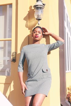 身着千鸟格连衣裙的优雅女子在明亮的阳光下于户外摆姿势，尽显复古美学