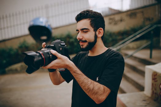 A young man focusing a DSLR camera outdoors, preparing for a photoshoot.