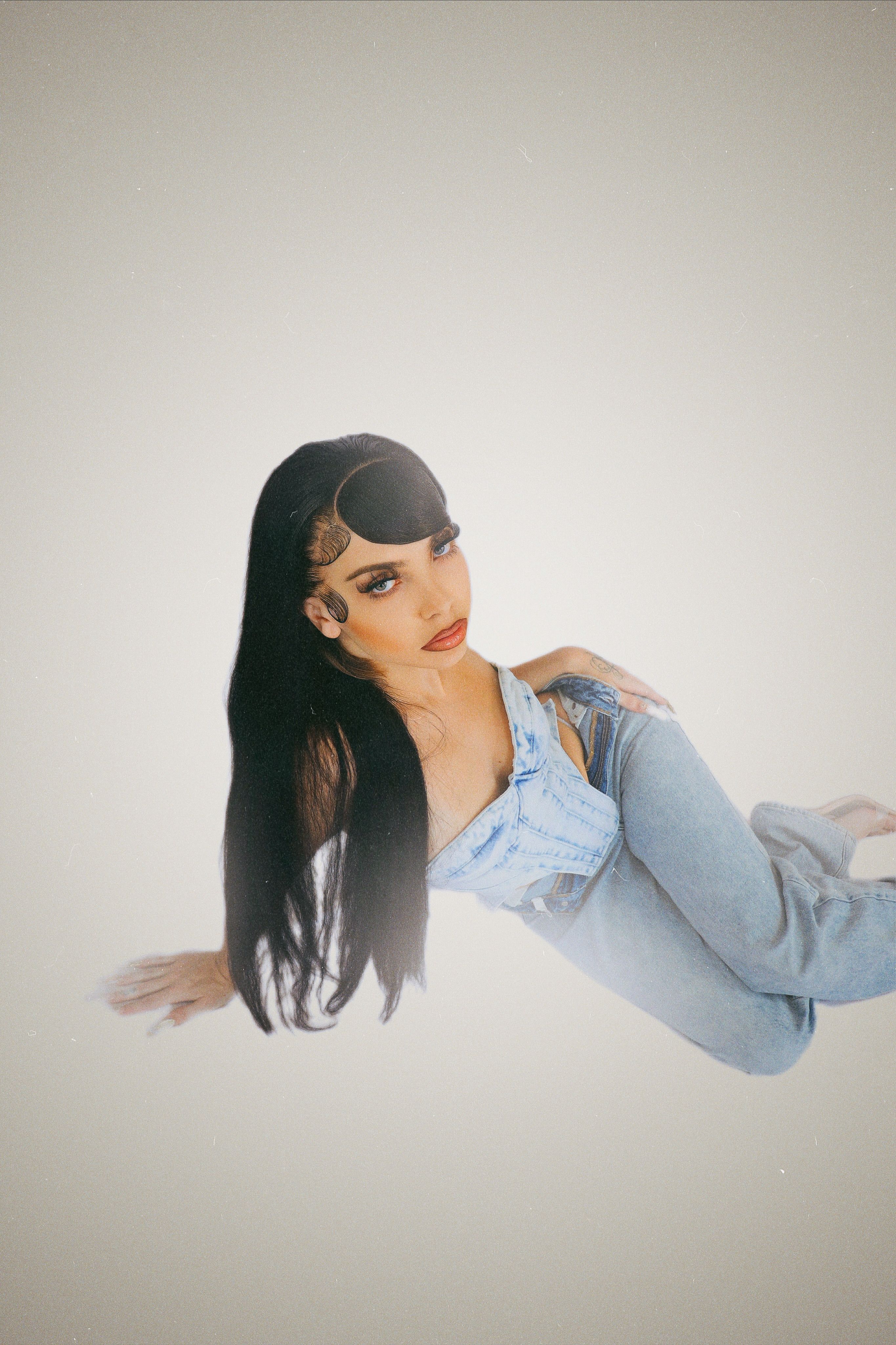 Stylish studio portrait of a woman in a denim corset and jeans, exuding elegance.