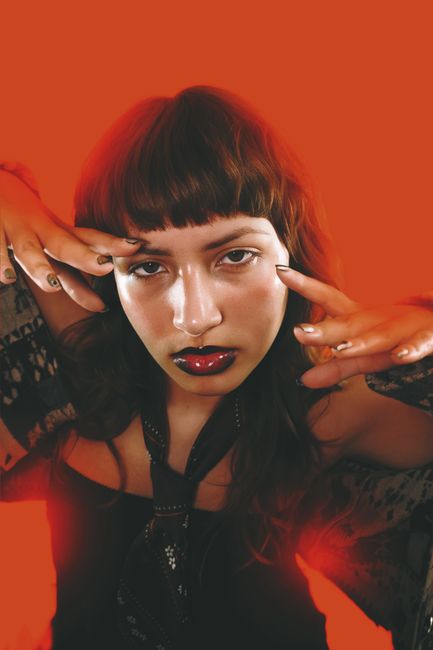 Artistic studio portrait of a woman with bold lipstick and bangs, featuring strong fashion elements.