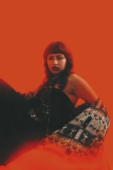 Stylish portrait of a woman posing elegantly against a bold red backdrop.