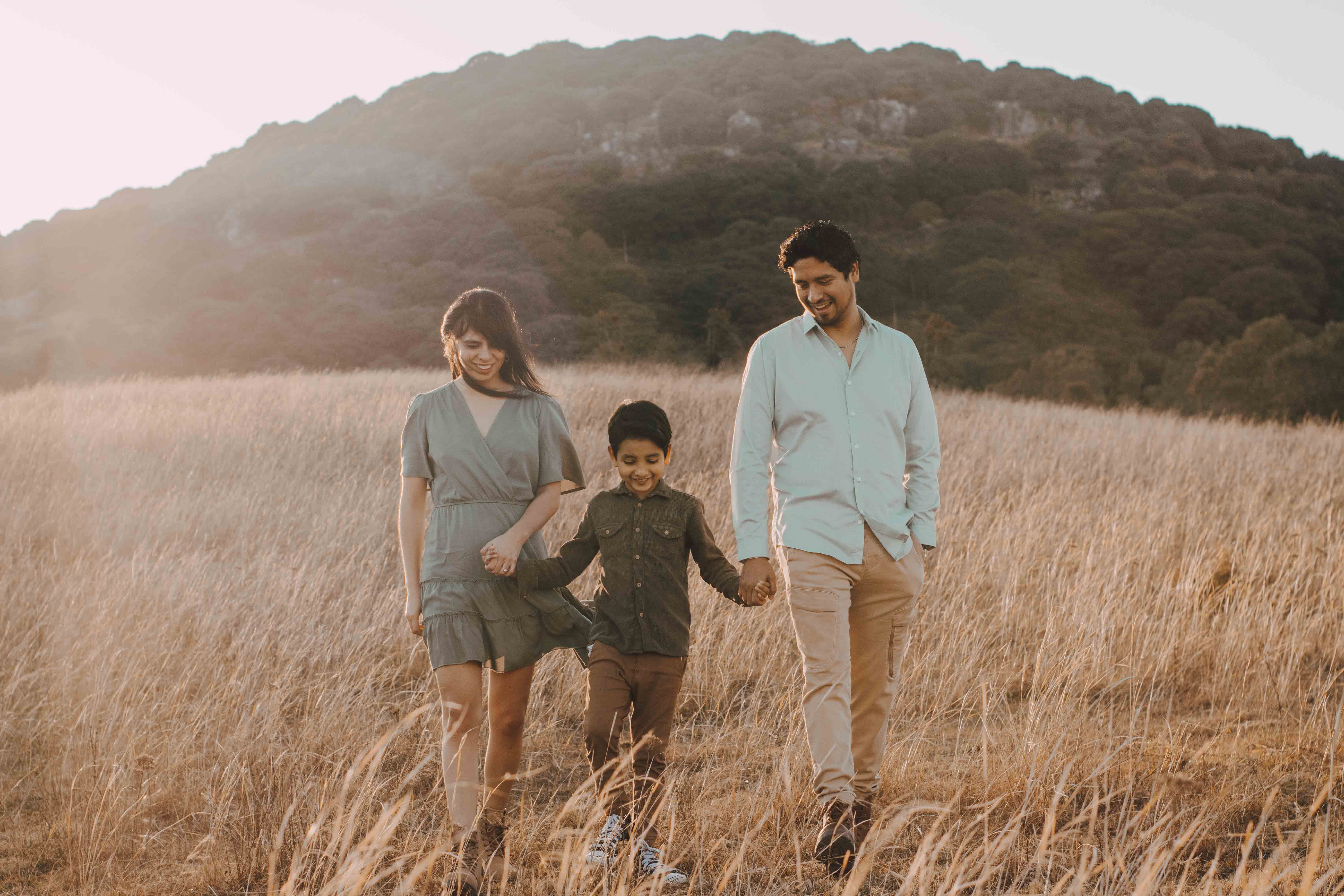 A family enjoying a sunny day in Álvarez, S.L.P., Mexico, walking hand in hand in a rural field.
