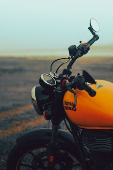 Detailed close-up of an orange Royal Enfield motorcycle with an outdoor backdrop.