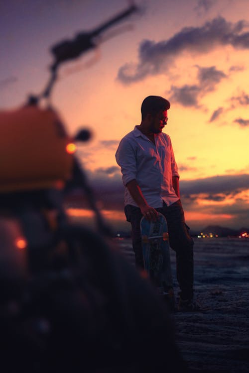 Man in Shirt and with Skateboard at Sunset