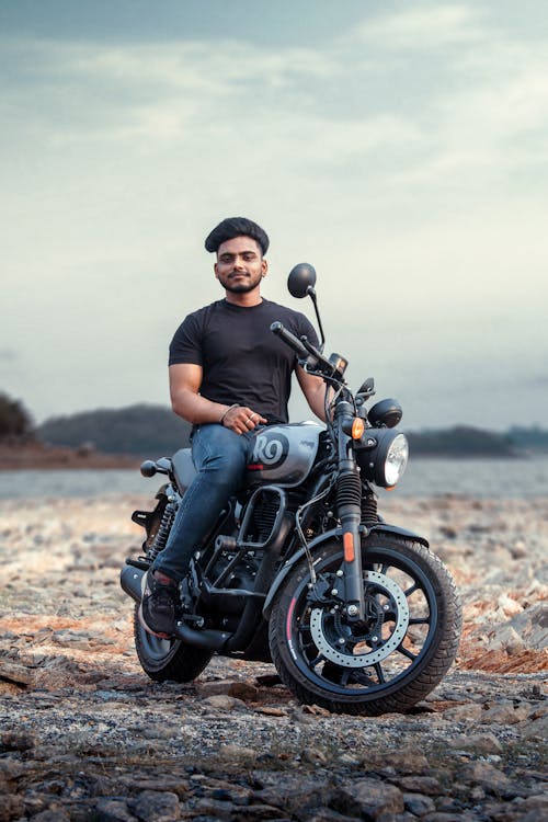 Man Sitting on a Motorcycle near a Body of Water 