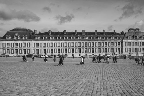 Free Black and white image of a historical baroque palace facade with people walking in Paris. Stock Photo