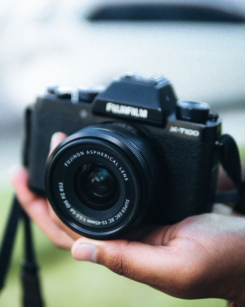 Free Close-up of hands holding a Fuji camera with lens outdoors, ideal for photography themes. Stock Photo