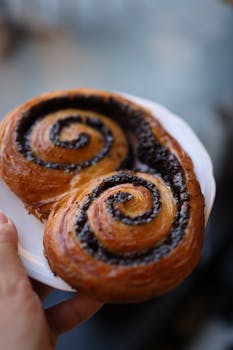 Delicious chocolate-filled swirled pastry held on a plate, perfect for dessert lovers.
