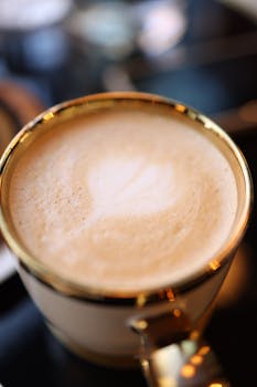 A close-up of a beautifully crafted frothy latte in a gold-rimmed cup, perfect for coffee lovers.