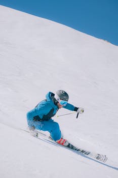 Skier in blue gear carving down snowy slope in Abruzzo, Italia during winter.