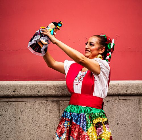 Free Mexican woman in traditional dress holding a doll, showcasing vibrant Puebla culture. Stock Photo
