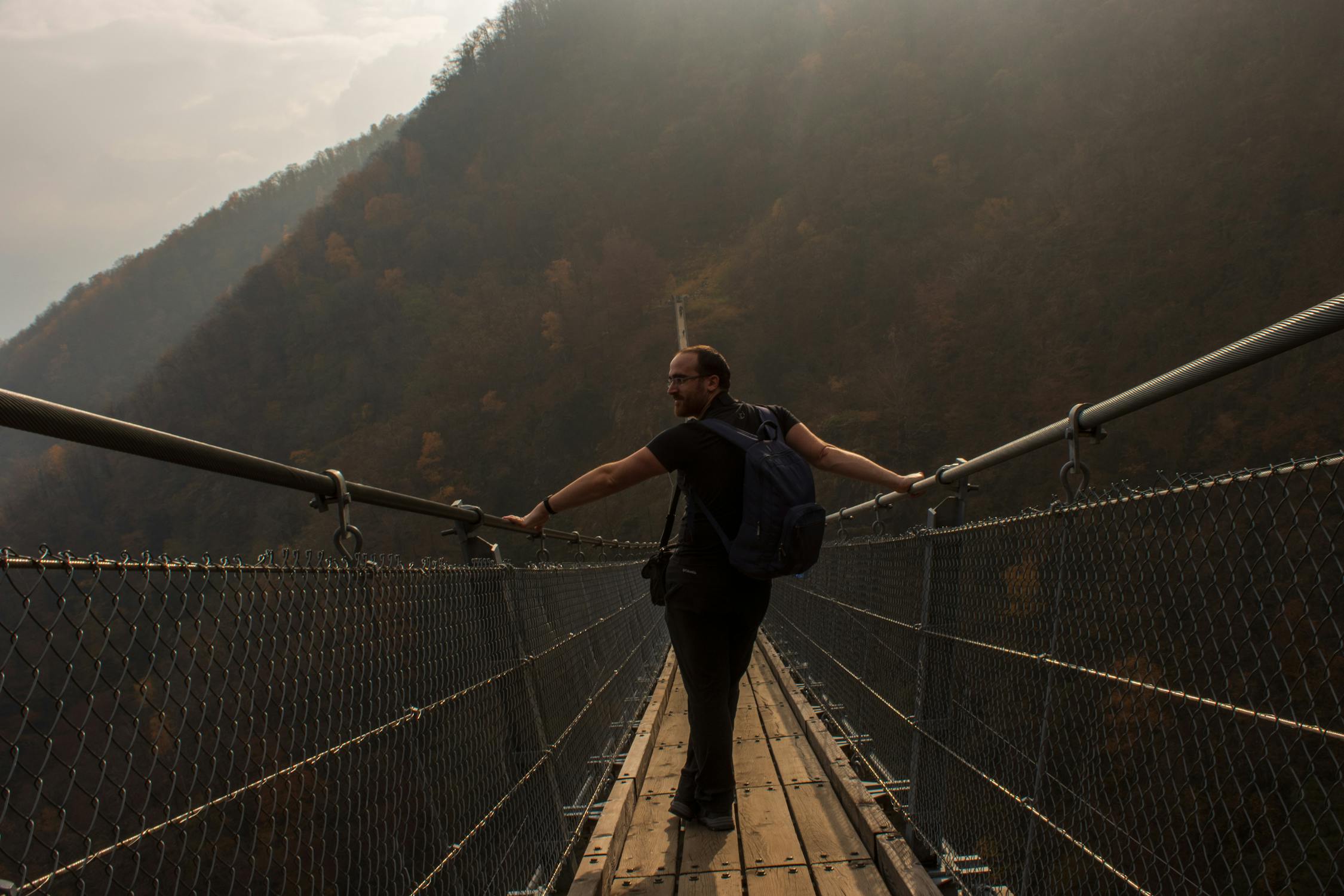 Man Standing on Wooden Footbridge in Mountains · Free Stock Photo