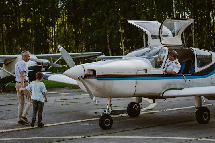 Father With Son Walking Near Light Aircraft