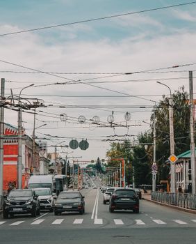 Busy city street intersection with cars, crosswalk, and traffic infrastructure in an urban setting.