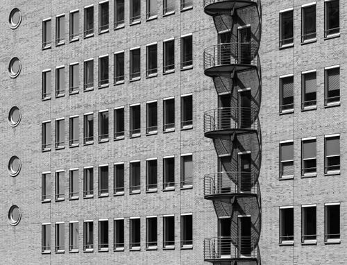 Free Monochrome image of a city building featuring a spiral fire escape. Stock Photo