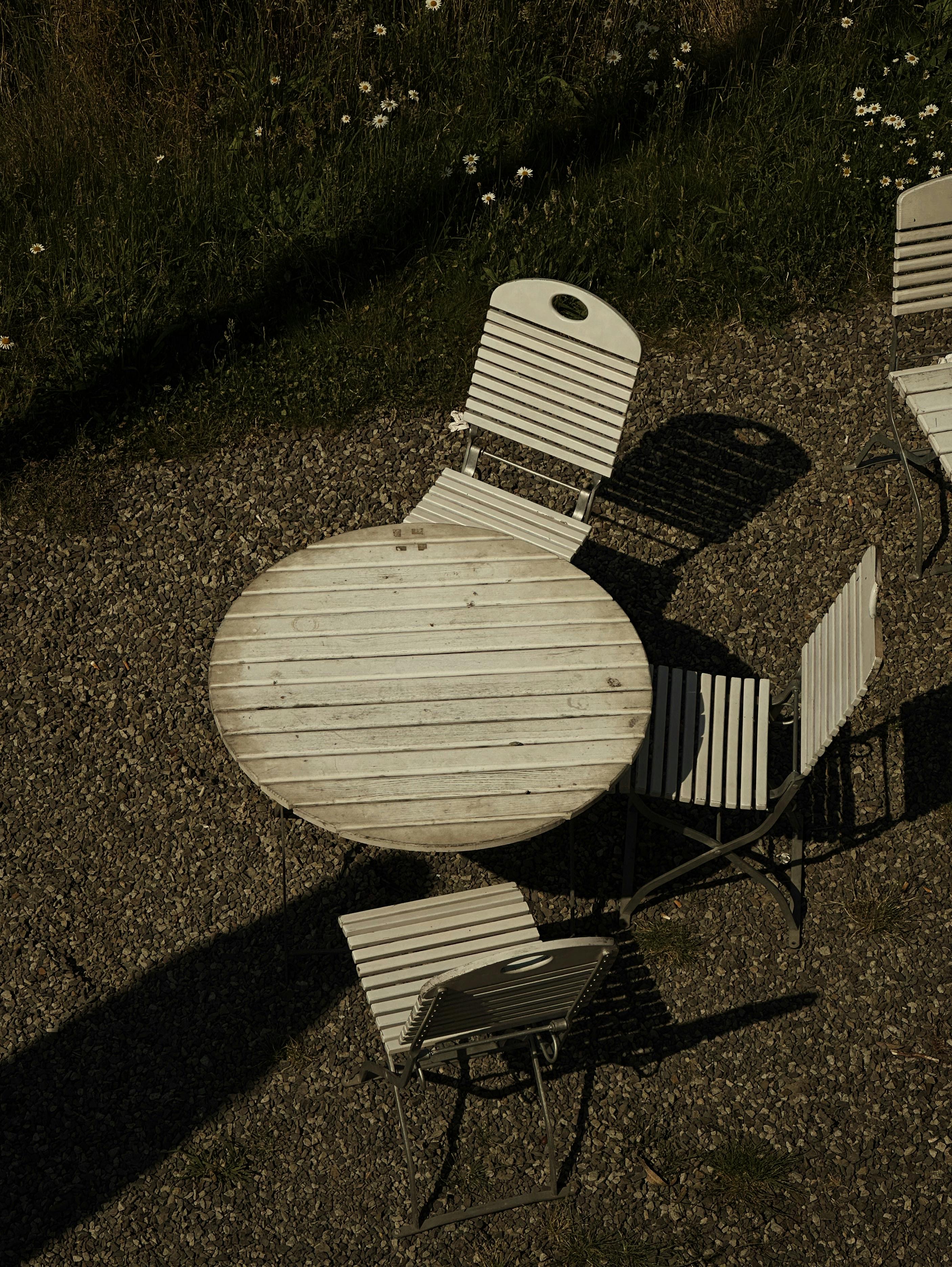 Aerial view of wooden patio furniture set on a gravel surface amidst greenery.