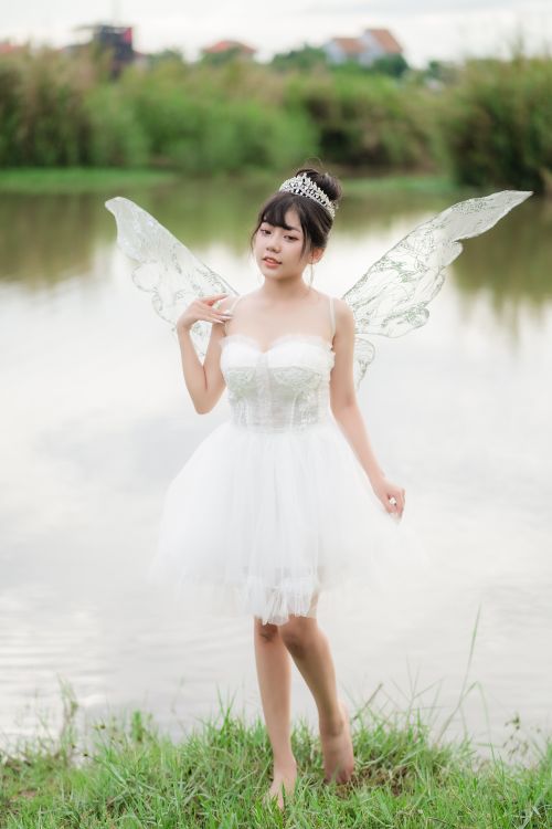 Free A woman dressed as a fairy bride poses gracefully by a tranquil lake, exuding ethereal charm. Stock Photo