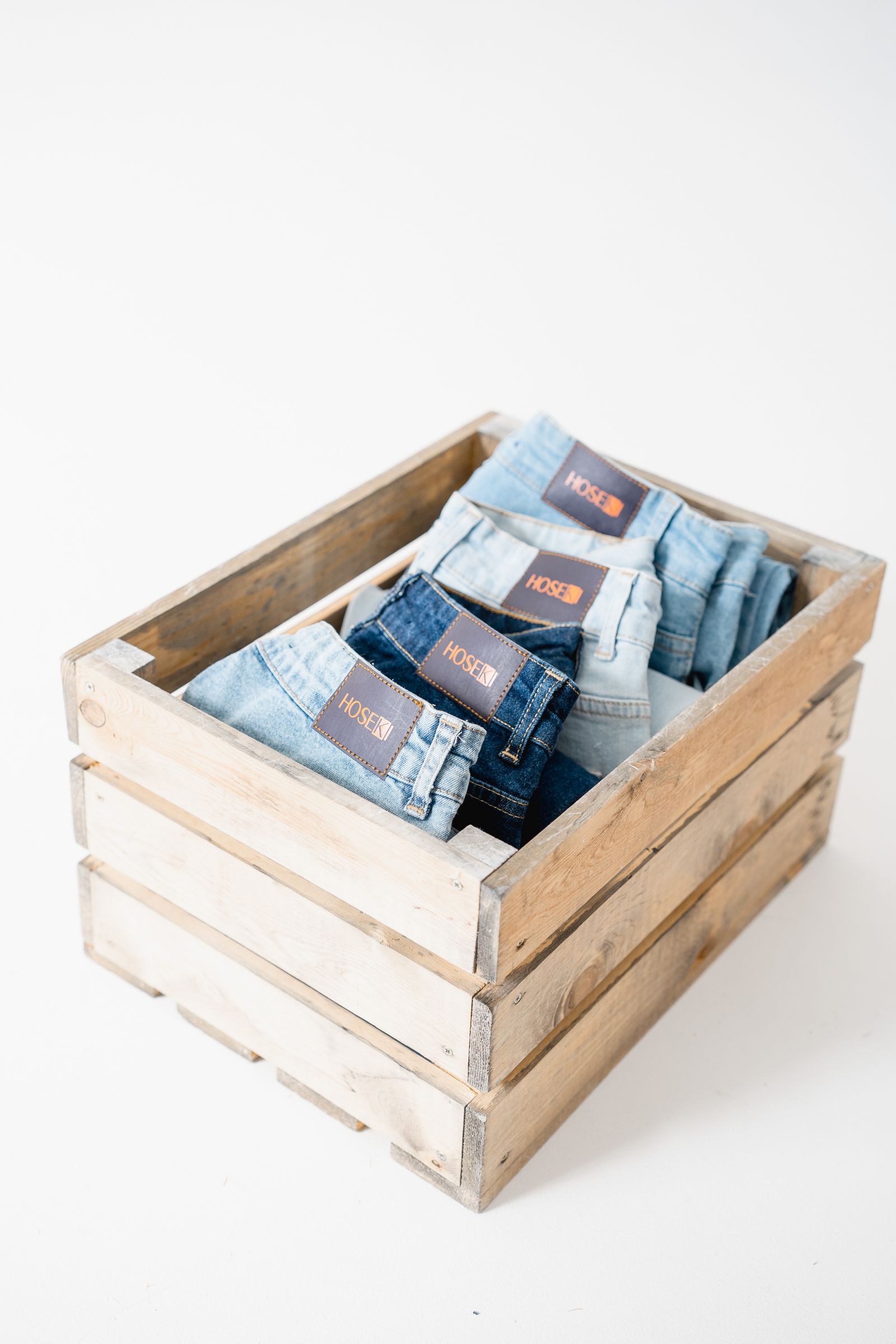 Neatly folded denim clothing stored in a wooden box without people