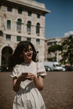 Stylish woman with smartphone enjoying a sunny day in Genoa, Italy.