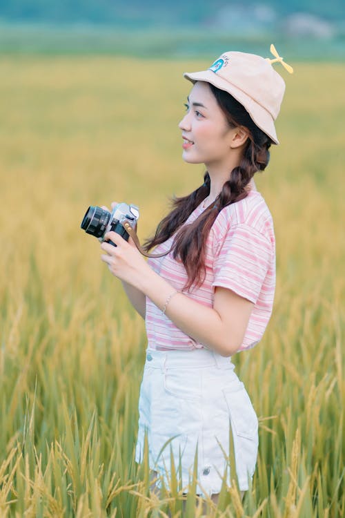 Young Girl with a Camera on a Grass Field 