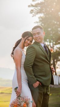 Romantic outdoor portrait of a couple embracing on their wedding day, bathed in sunlight.