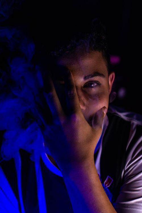 Free Young man with hand on face illuminated by blue and purple lighting for dramatic effect. Stock Photo