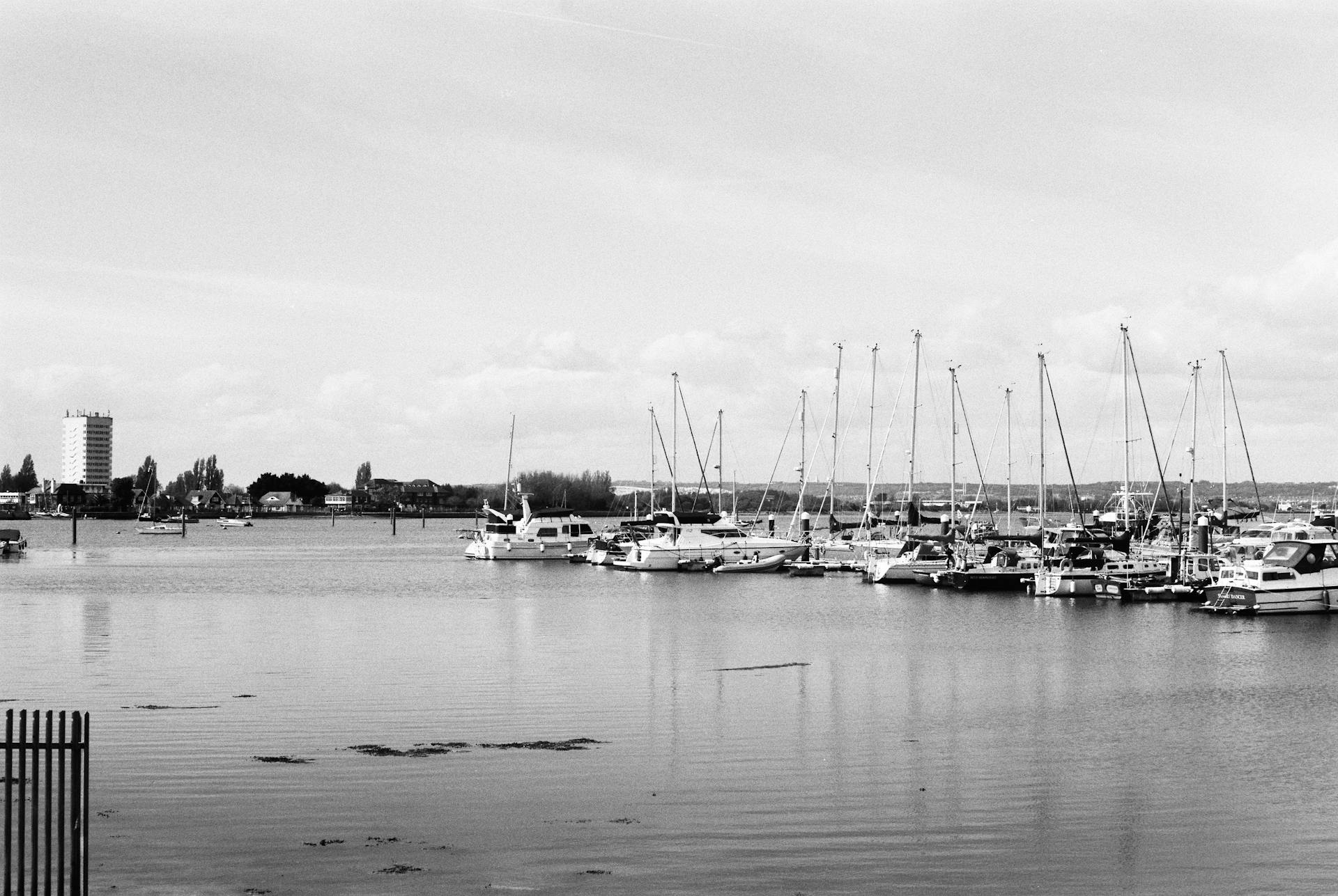 A calm marina with motor yachts and sailboats moored, captured in black and white, exuding tranquility.