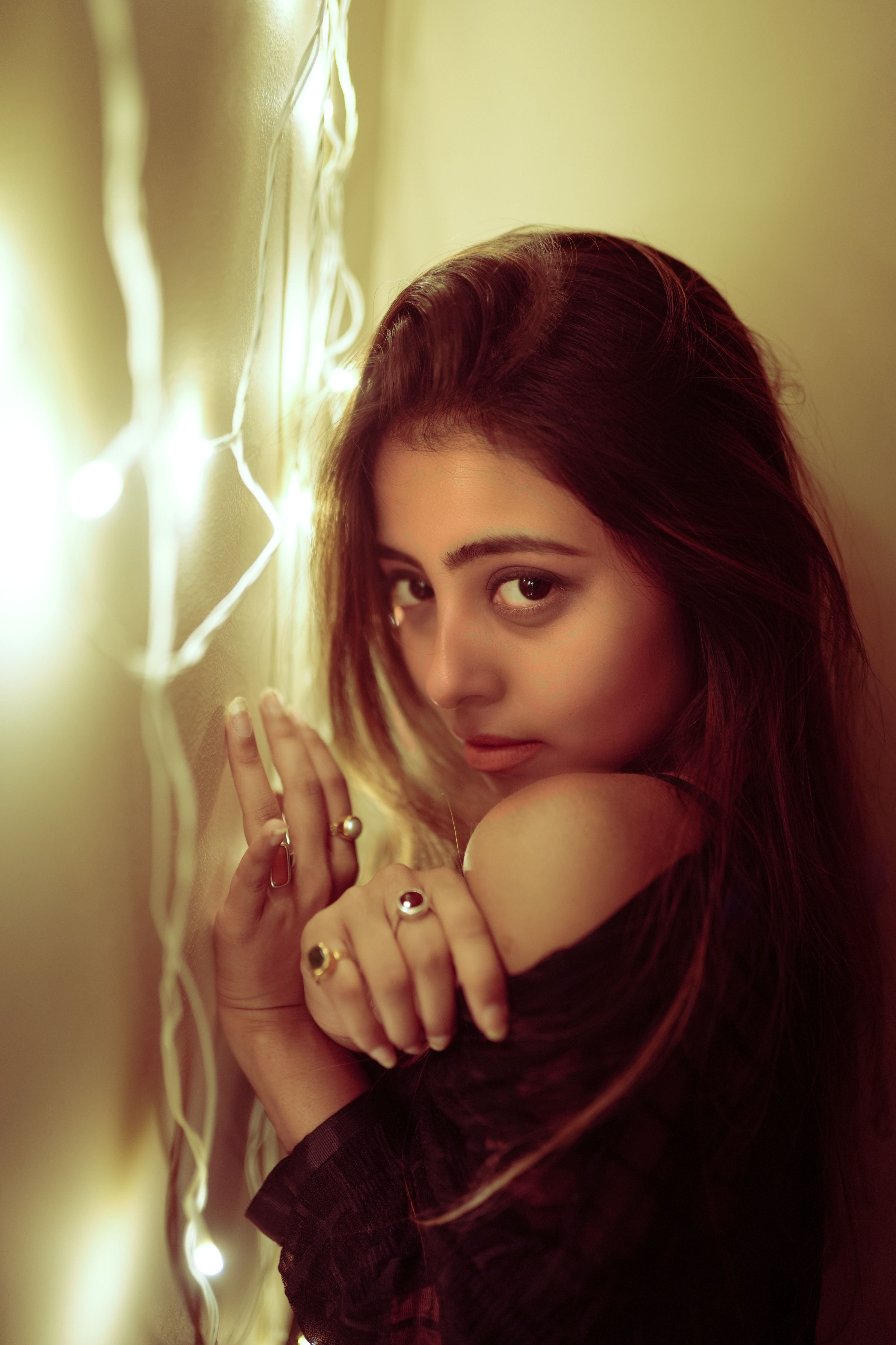 Artistic portrait of a young woman with fairy lights, exuding a warm and moody atmosphere.